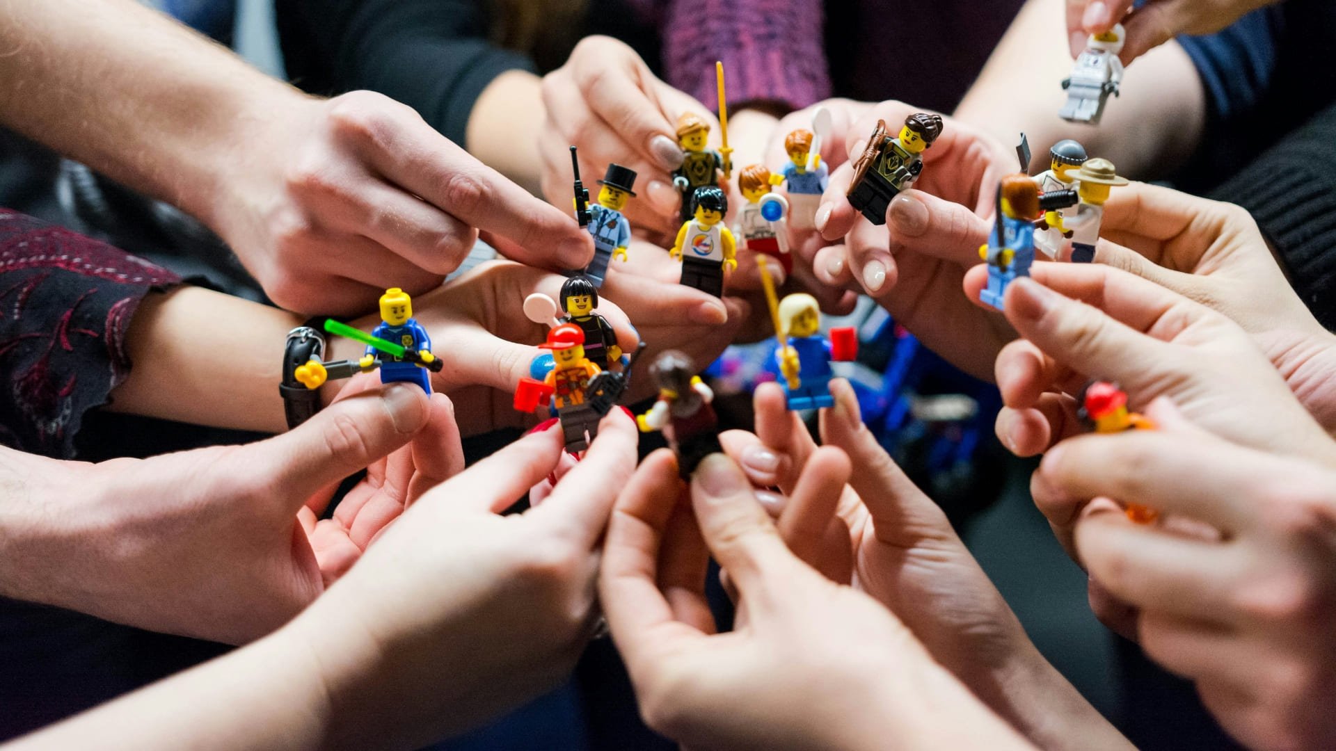 Plusieurs mains tendues tenant des figurines Lego, illustrant la notion de la marque employeur