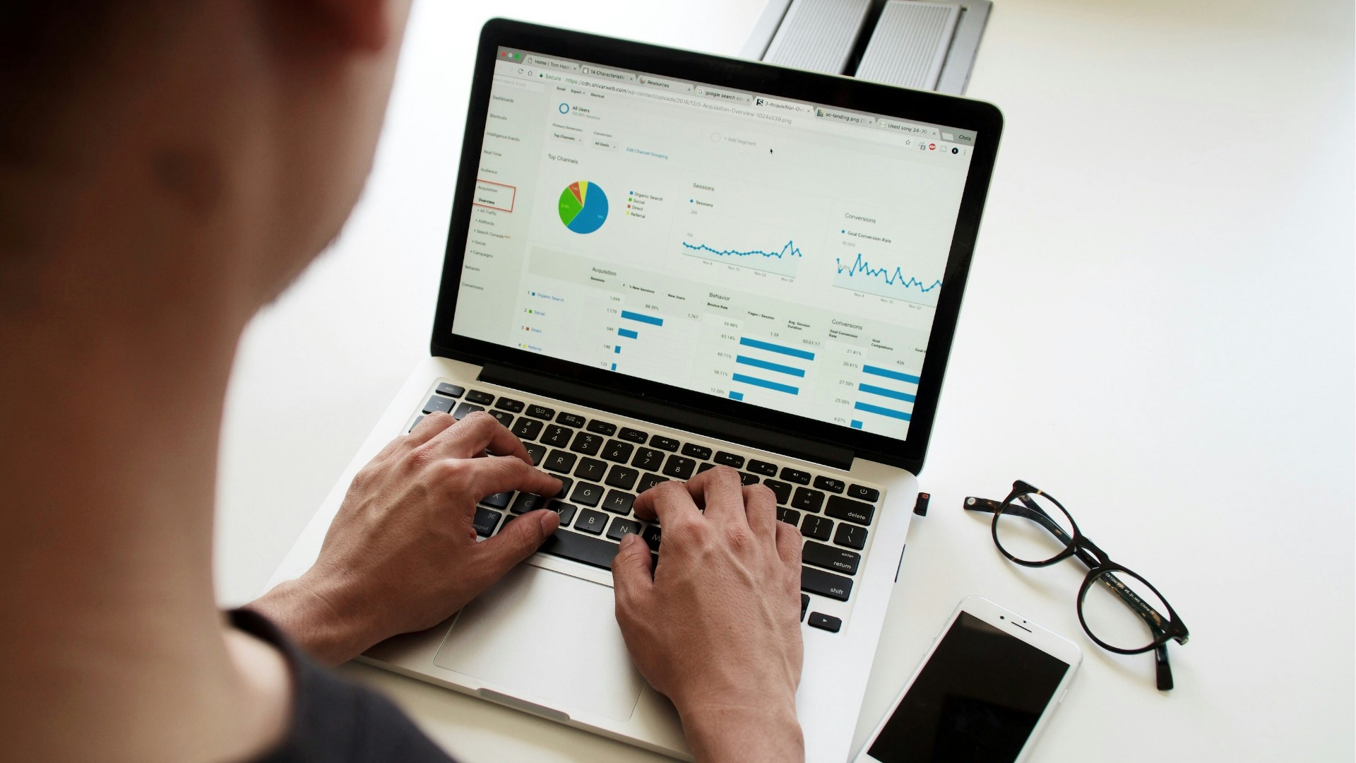 Personne analysant les statistiques de performance d’un site web sur un ordinateur portable à l’aide de Google Analytics, illustrant l’importance du suivi des conversions et du comportement des utilisateurs.