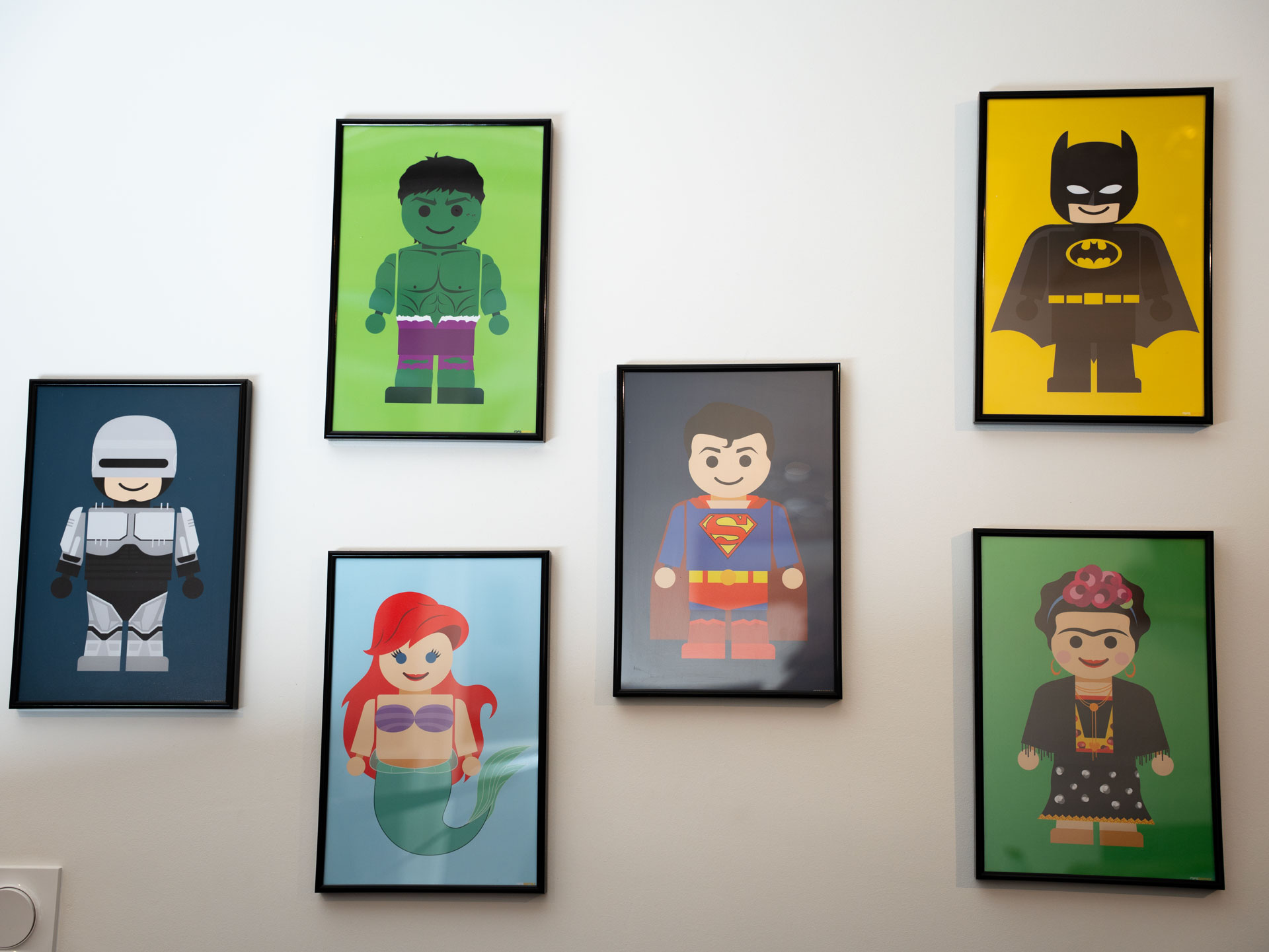 Mur du Studio Ikadia sur lequel des portraits de héros sont disposés